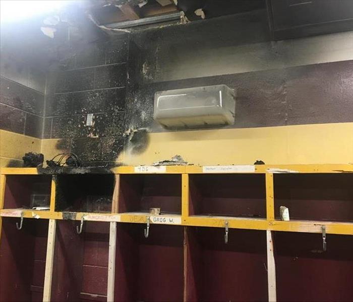 Fire and smoke damage on a ceiling and wall in a locker room. 