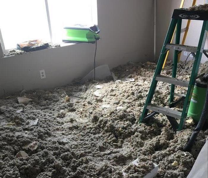 A floor covered in ceiling material and insulation after demolition has taken place. 