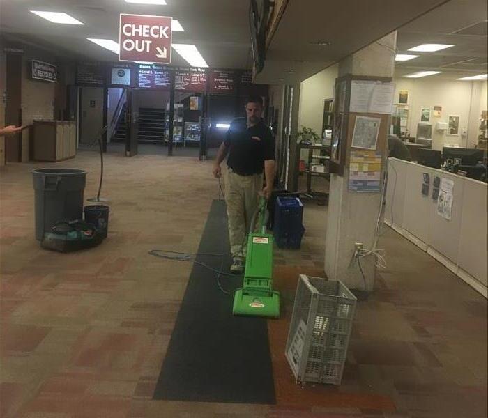 A technician vacuuming a carpet after a counter was removed. 