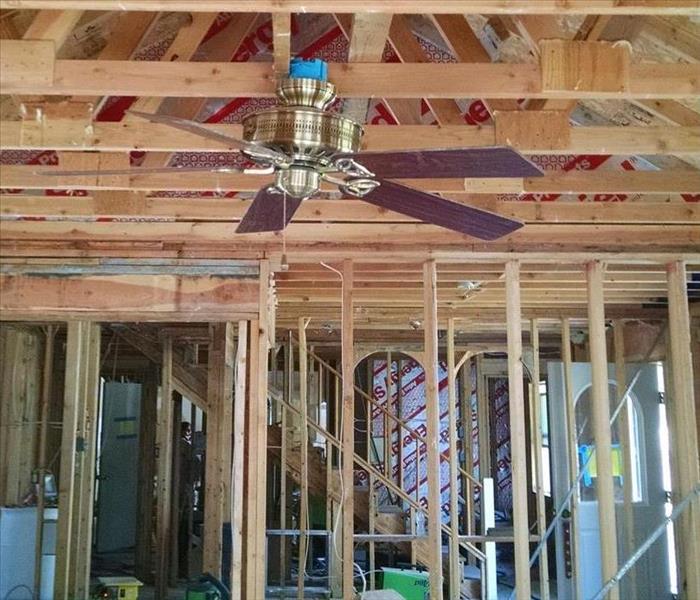 A home gutted down to the framing and a single ceiling fan. 