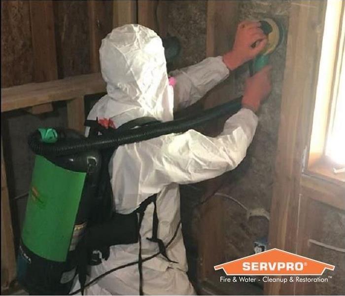 SERVPRO technician sanding mold from wall cavity.