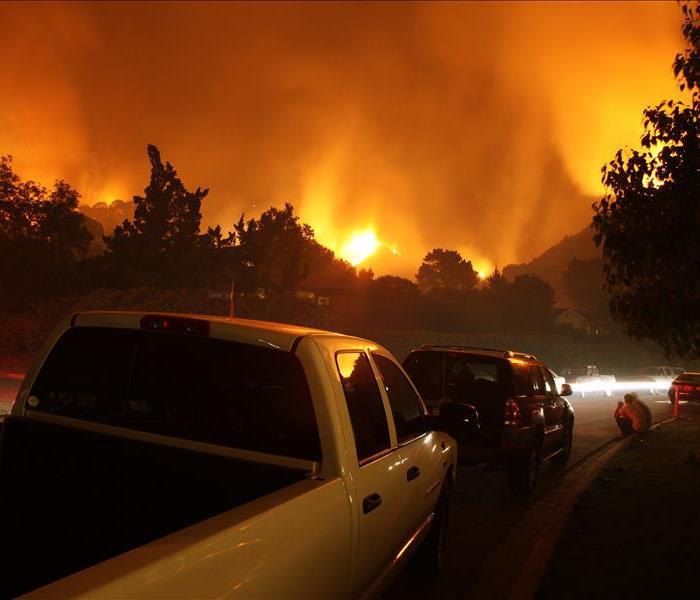 Cars evacuate an area surrounded by forest fire.